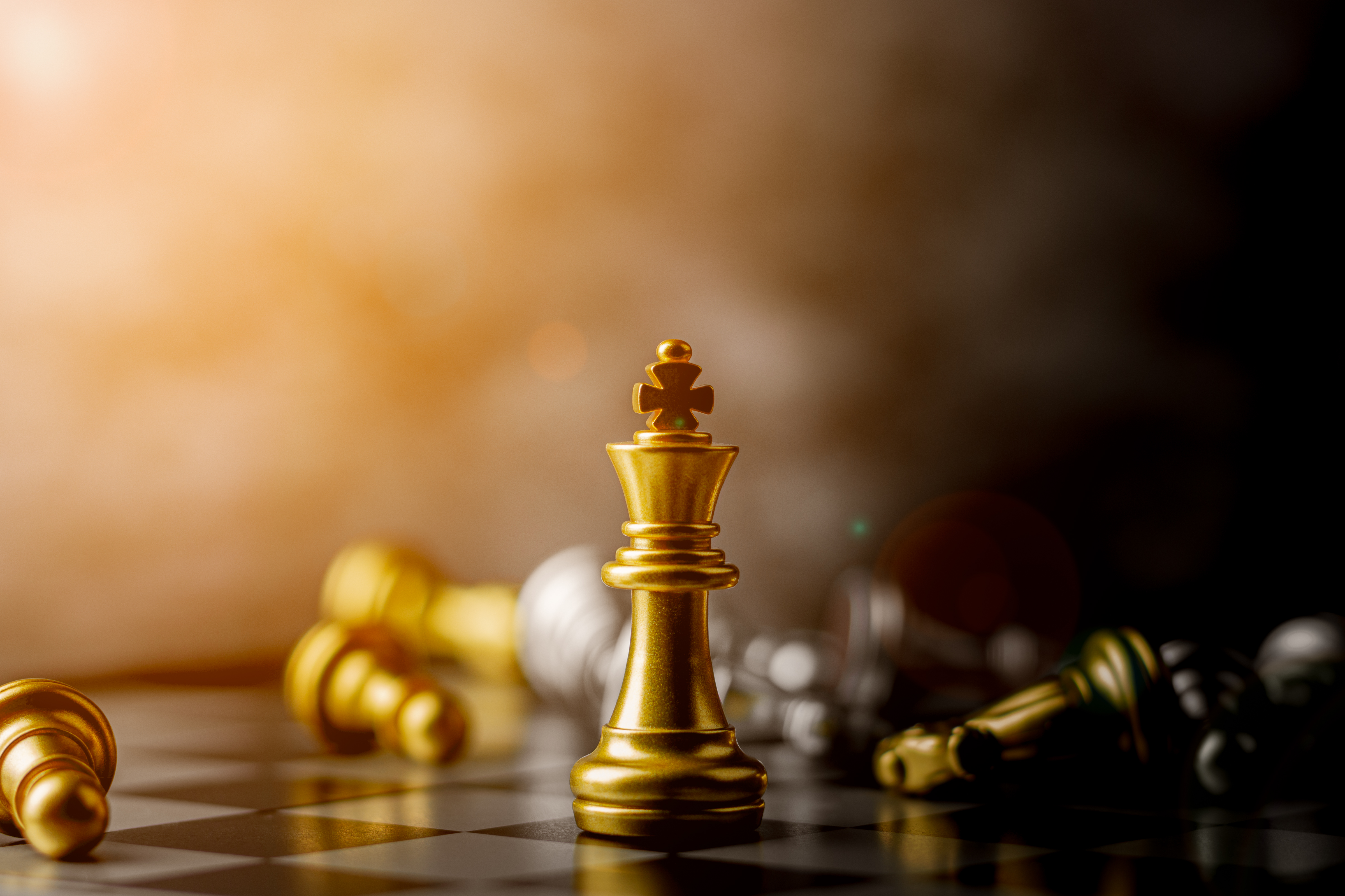 Golden king chess piece standing among defeated opponents — representing market dominance